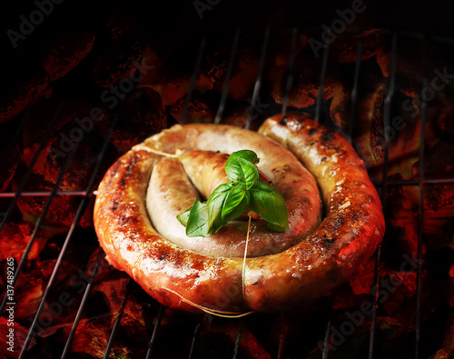 Photos cumberland sausage, spiral pork sausage on bbq grill with flame, homemade