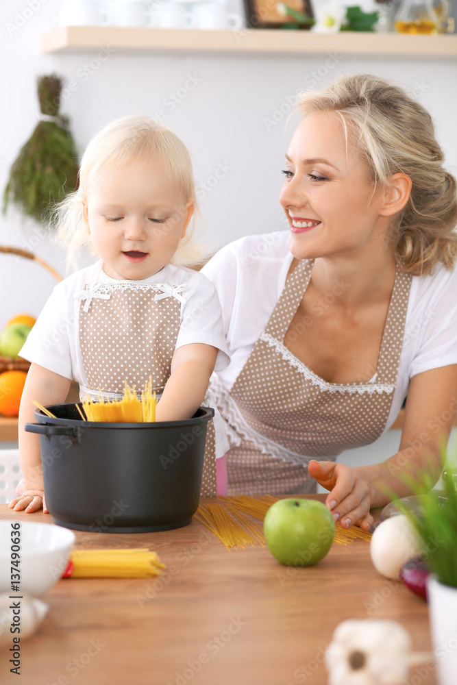 Happy family in the kitchen. Mother and child daughter cooking pasta for the breakfest Happy family in the kitchen. Mother and child daughter cooking pasta for the breakfest