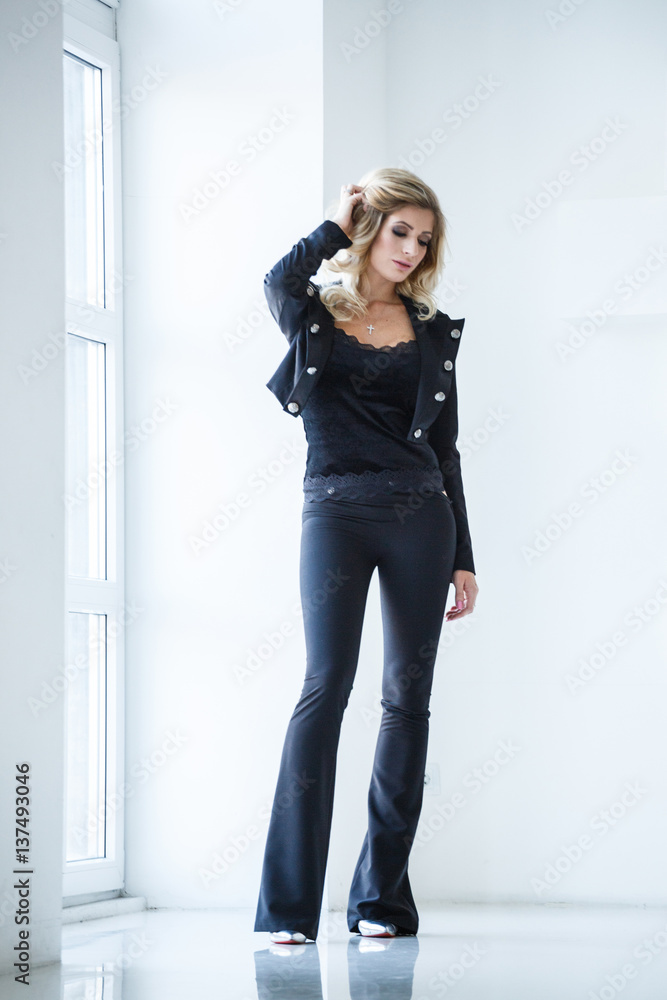 Beautiful sexy blonde in a white suit (pants, jacket) posing on white background Beautiful sexy blonde in a white suit (pants, jacket) posing on white background