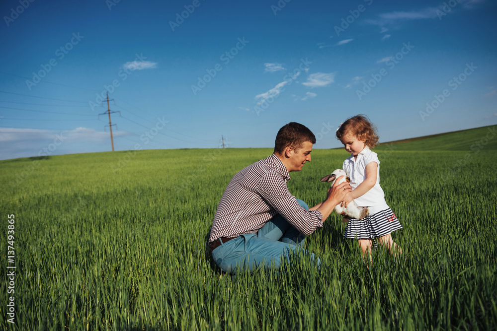 Happy father and baby rabbit on hands in field Happy father and baby rabbit on hands in field