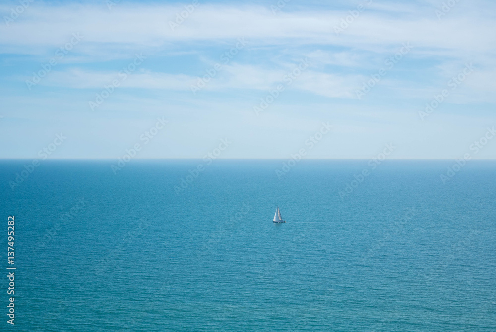 A lonely sailing ship in the water of English Channel on cloudy day, Seven Sisters country park.