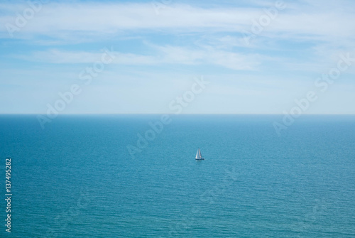 A lonely sailing ship in the water of English Channel on cloudy day, Seven Sisters country park.