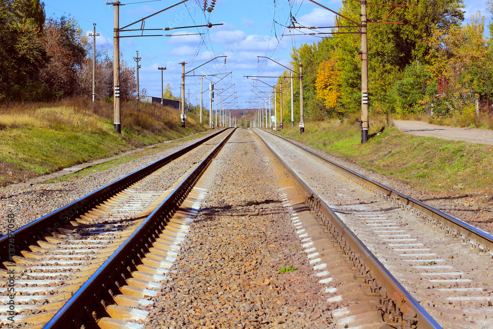 Railroad among an autumn forest. Electrical wires on poles