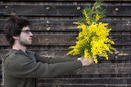 Bild auf Leinwand Ragazzo sta regalando un mazzo di mimose alla sua ragazza visto di profilo