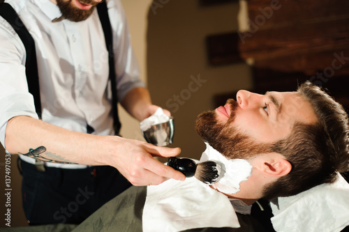 Master cuts hair and beard of men in the barbershop © nagaets