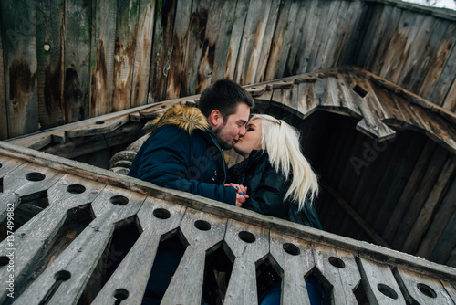 winter love story. young beautiful couple kissing under the roof of wooden house