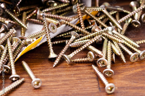 Yellow passivated screws on wood desk photo