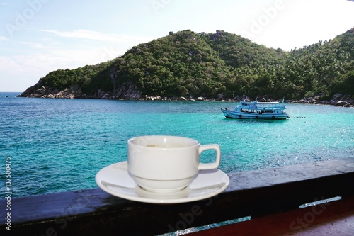 a cup of coffee with blue sea as background photo