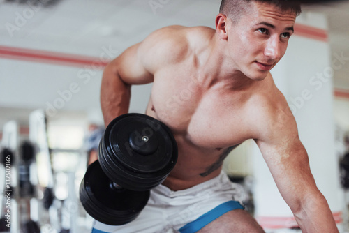 Portrait of a beautiful athletic guy muscles with weights