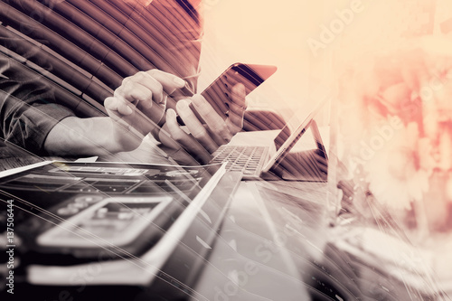 double exposure of businessman hand using smart phone,mobile payments online shopping,omni channel,digital tablet docking keyboard computer,flower glass vase on wooden desk,London architecture city