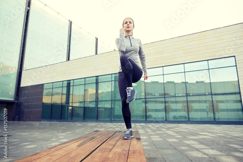 woman making step exercise on city street bench