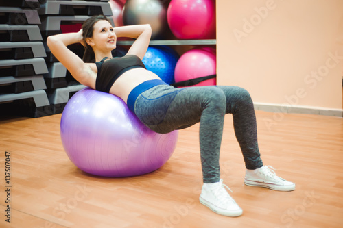 Pretty sexual straight fitness woman with musculat body lying on big ball in sport hall training indoor, horizontal picture