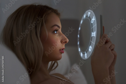 young woman reading horoscope on smartphone photo