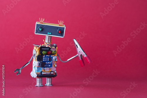 Friendly robotic handyman toy with red pliers. Pink background copy space.