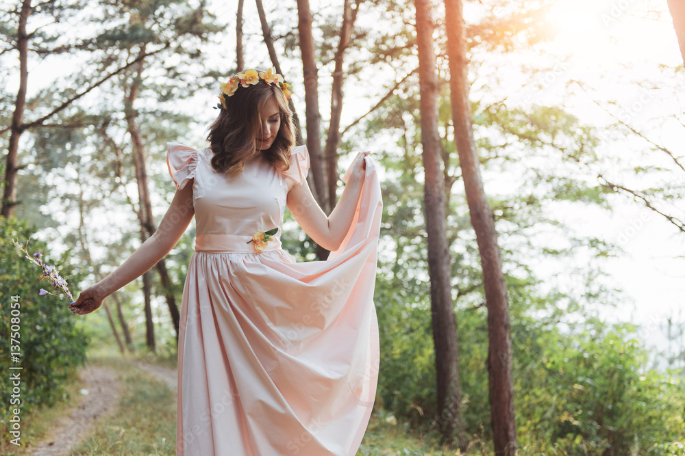 Naklejka premium Happy young woman in long dress a beautiful pine forest