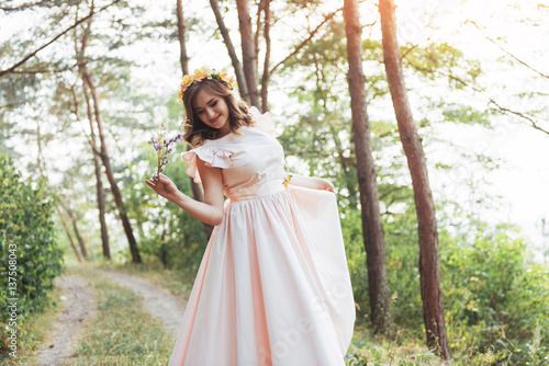 Happy young woman in long dress a beautiful pine forest