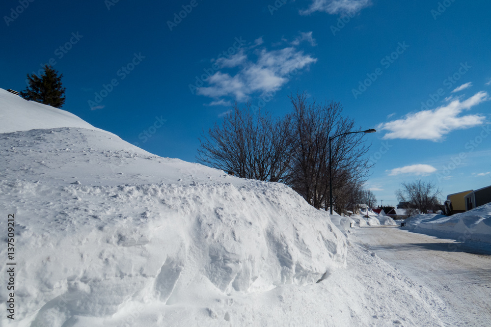 Obraz premium Ogromny snowbank zaorany z ulicy po wielu zimowych burzach podjętych w piękny zimowy dzień. Levis, Quebec, Kanada.