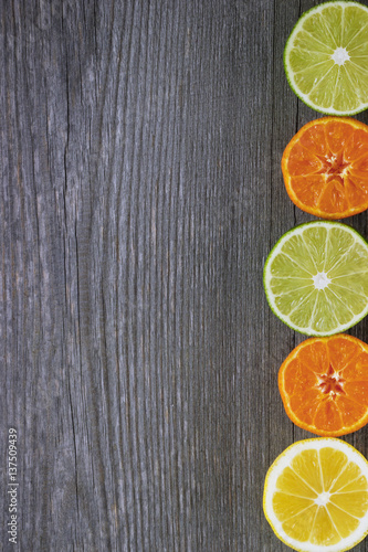 Lemons, tangerines and limes on grey wooden table.