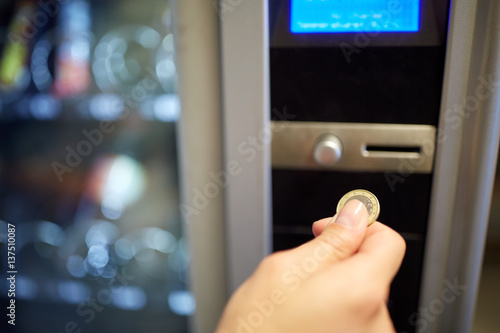 hand inserting euro coin to vending machine slot