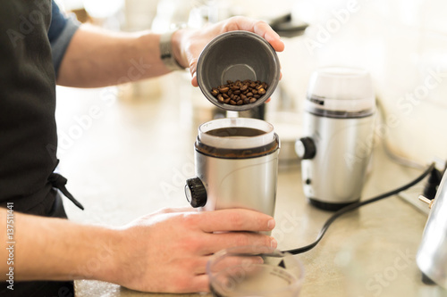 Pouring coffee grains on a grinder