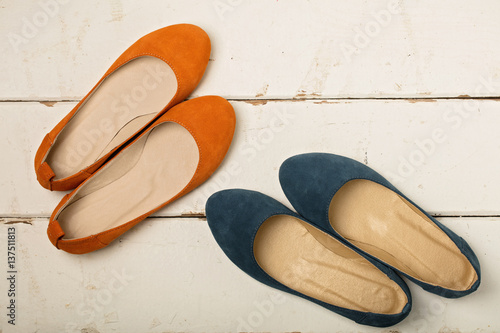Blue and orange women's shoes (ballerinas) on wooden background.