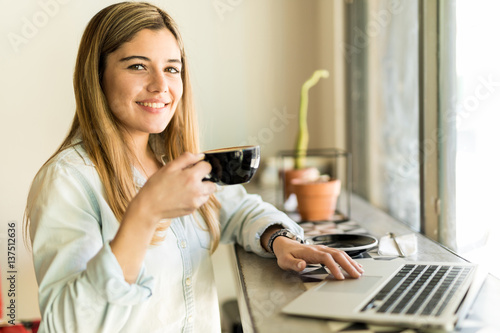 Hispanic woman drinking coffee and working