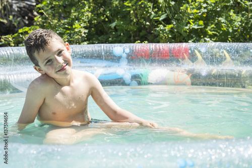 In the summer in the garden boy bathes in inflatable pool. © tsomka