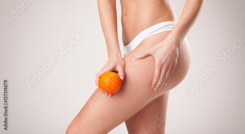  Jeune femme tenant une orange sur le haut de sa cuisse
