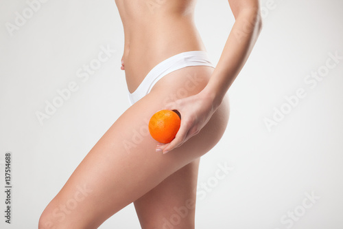 Jeune femme tenant une orange sur le haut de sa cuisse