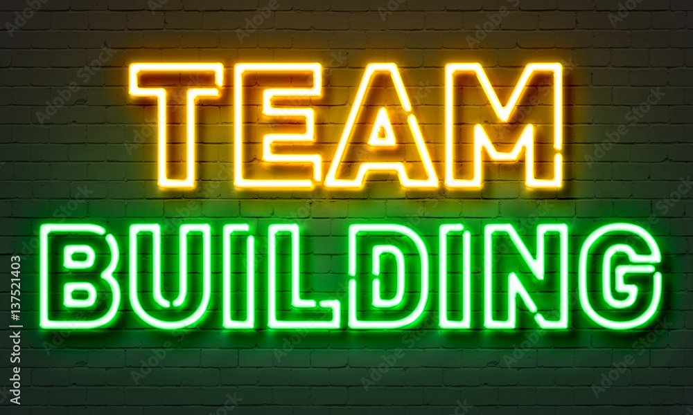 Team building neon sign on brick wall background.