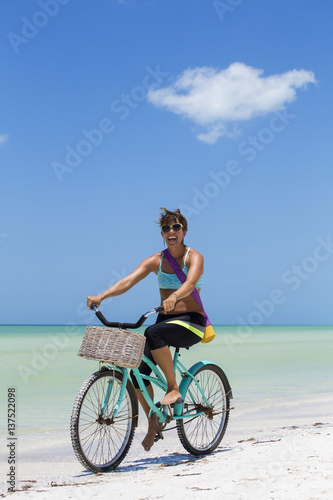 Woman rides bike to yoga at the beach