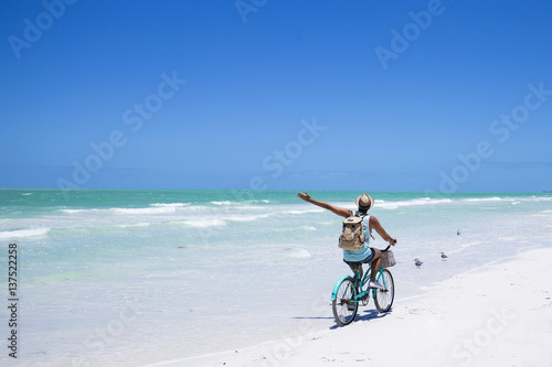 Tourist riding a bike on the beach.