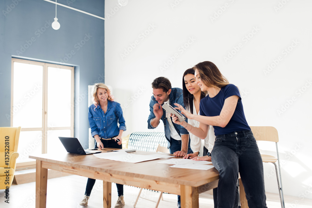 Group of young coworkers using a digital tablet while brainstorming in the office Group of young coworkers using a digital tablet while brainstorming in the office