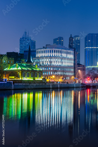 River And Modern Buildings Against Sky at night.