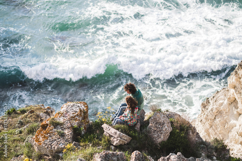 Man and woman in love standing on edge of cliff. Beautiful view of rocks and sea waves © Oleg Breslavtsev
