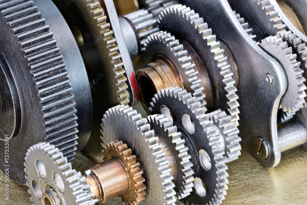 Fototapeta premium various gear cogwheels on scratched metal industrial background macro view