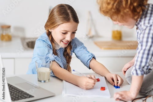 Happy smart girl doing homework with her brother