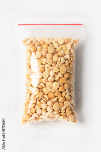 Plastic transparent zipper bag with full raw organic split peas isolated on white, Vacuum package mockup with red clip. Concept
