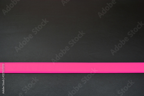 Pink stripe on black background. Belt from leather. Line with pink color
