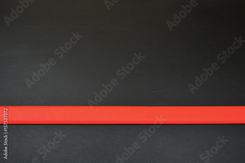 Red stripe on black background. Belt from leather. Line with red color © Sergey