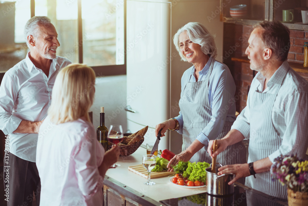 Obraz premium Cheerful aged couples cooking in the kitchen