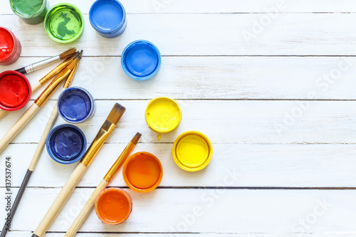 Paints and brushes on a white wooden background