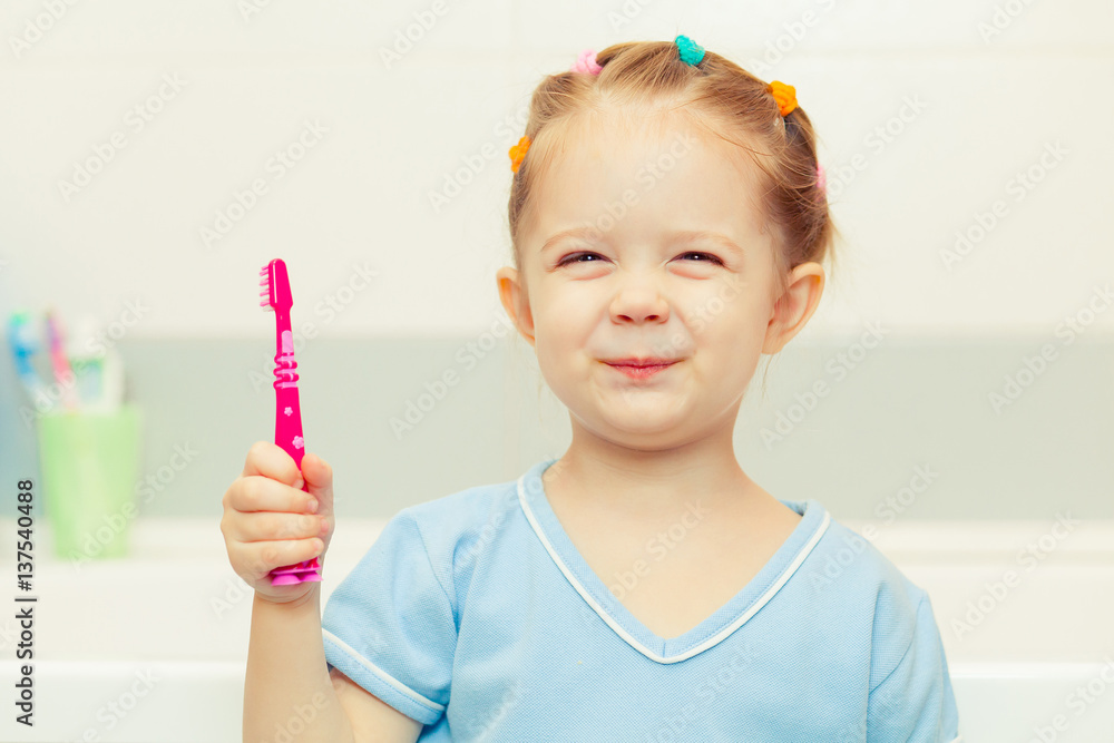 Little girl brushing her teeth in the bathroom. Smiling child holding a toothbrush. Little girl brushing her teeth in the bathroom. Smiling child holding a toothbrush.