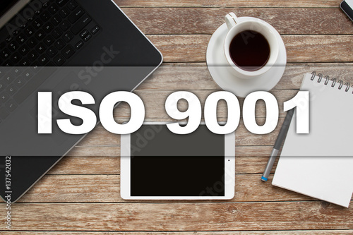 Tablet on desktop with iso 9001 text.