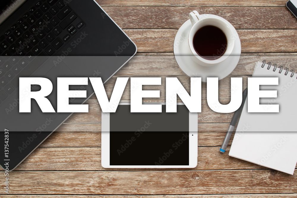 Tablet on desktop with revenue text. Tablet on desktop with revenue text.