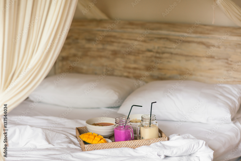 Healthy Raw Fruit Breakfast in Bed. Color Smoothie on Wicker Tray on White Sheet. Healthy Raw Fruit Breakfast in Bed. Color Smoothie on Wicker Tray on White Sheet.