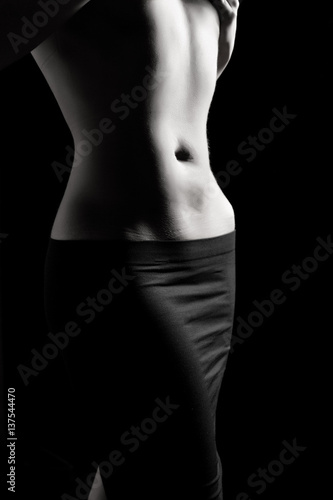female belly and bodypart of a young athletic girl on a dark background