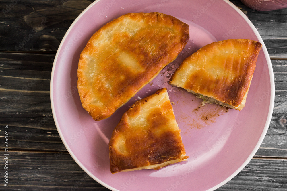Pasties with meat, and a mug of tea on a wooden table in a rustic style. Pasties with meat, and a mug of tea on a wooden table in a rustic style.