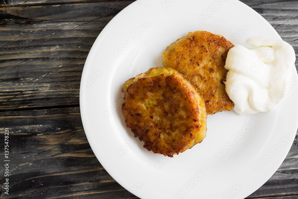Potato patties with sour cream on a wooden table in rustic style Potato patties with sour cream on a wooden table in rustic style