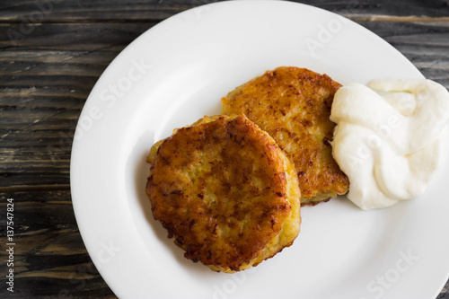 Potato patties with sour cream on a wooden table in rustic style